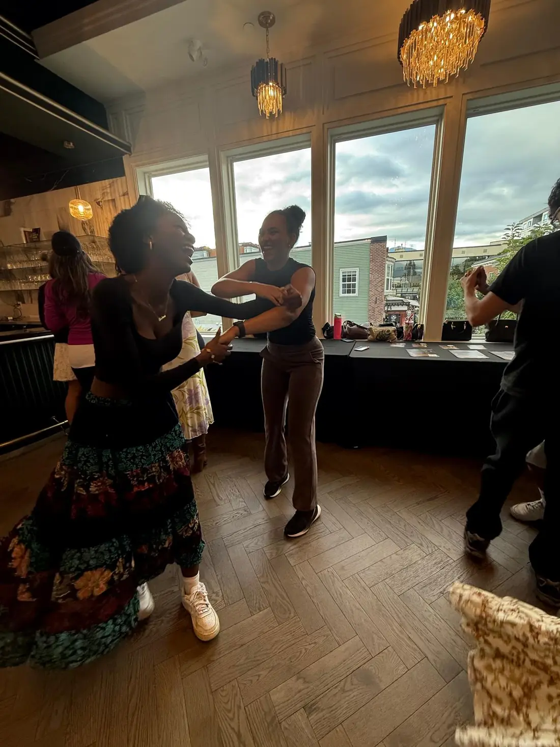 Two dancers laughing together as the floor fills around them