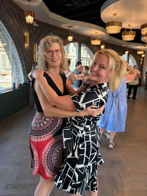 Two dancers laughing in an embrace after their rotation at Tuesday Salsa Nights, The Grand Hall