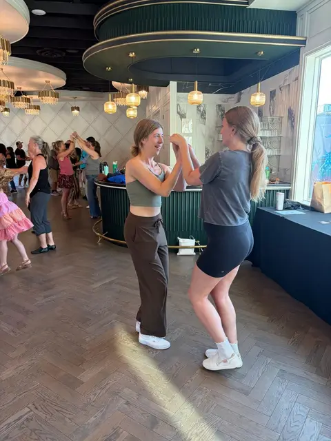 Two dancers practising an underarm turn hand connection by the bar at The Grand Hall, District 1881