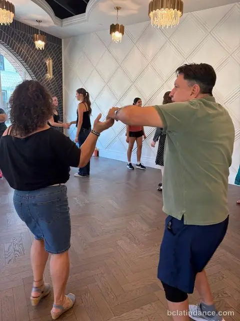 Dancers rotating partners against the white panelled wall at The Grand Hall, Chilliwack