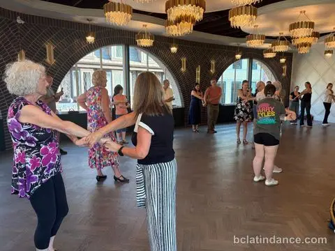 The class in colourful dresses lined along the arched windows at Tuesday Salsa Nights, The Grand Hall