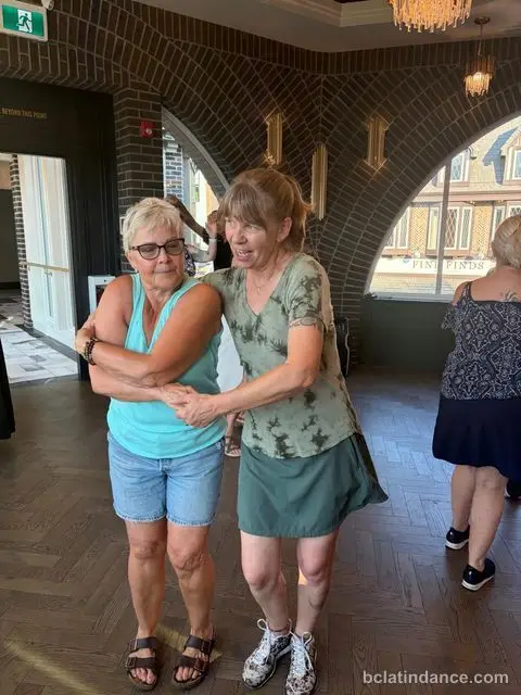 Two friends dancing close hold by the arched windows at The Grand Hall, Chilliwack