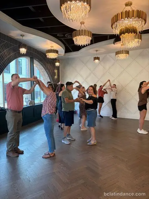 Couples forming an overhead hand-chain by the arched windows at The Grand Hall, District 1881, Chilliwack