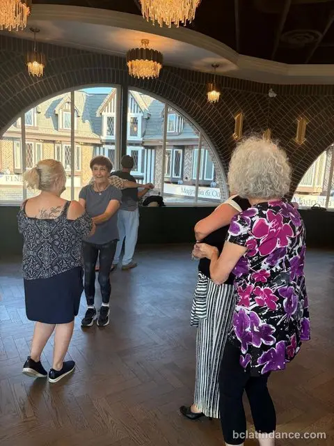 Two friends practising close hold by the arched windows at Tuesday Salsa Nights, The Grand Hall, Chilliwack