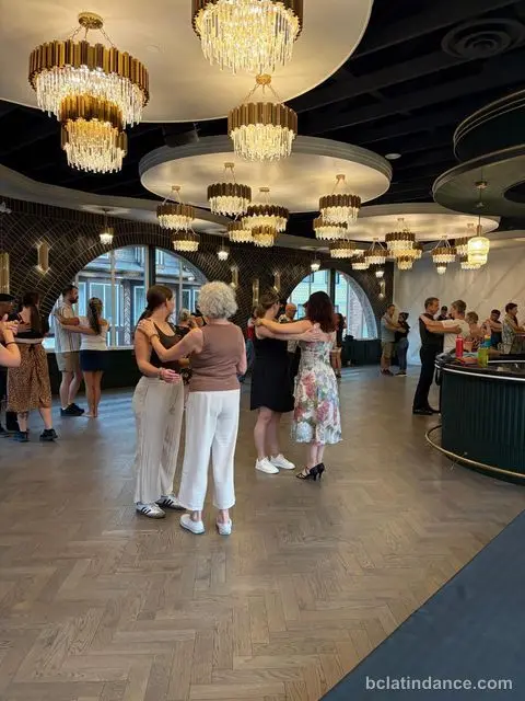 Couples in close hold beneath the chandeliers at Tuesday Salsa Nights, The Grand Hall, Chilliwack