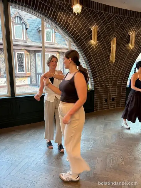 A lead-and-follow pair working by the arched window at Tuesday Salsa Nights, The Grand Hall, Chilliwack
