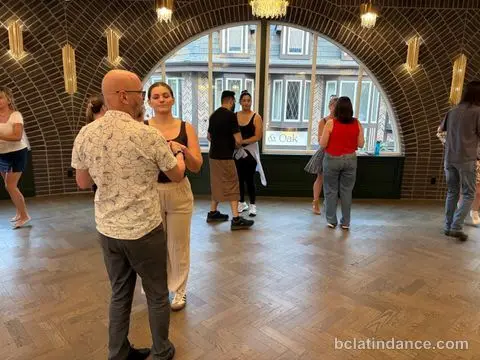 Salsa Paul dancing with a student by the arched windows at The Grand Hall, Chilliwack