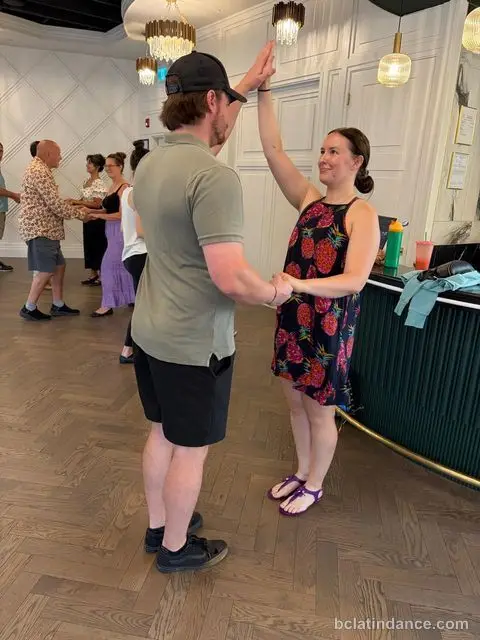 A couple taking an underarm turn beside the bar at Tuesday Salsa Nights, The Grand Hall, Chilliwack