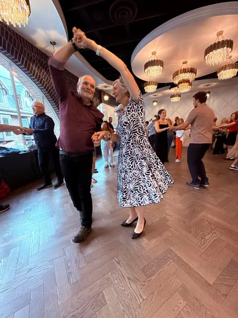 An underarm turn beneath the chandeliers at The Grand Hall, Chilliwack