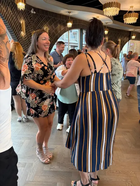 Two women laughing through a partner rotation at Tuesday Salsa Nights in Chilliwack