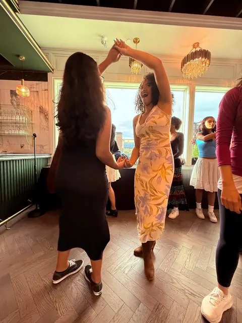 Two dancers laughing through a turn at Tuesday Salsa Nights in Chilliwack