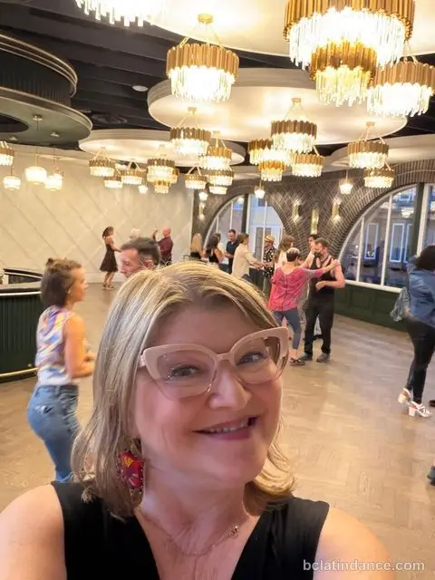 A dancer smiling for the camera with the class dancing behind her at Tuesday Salsa Nights, The Grand Hall, District 1881, Chilliwack