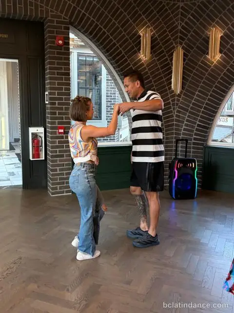 Two dancers working an underarm turn beneath the brick arch at The Grand Hall, Chilliwack