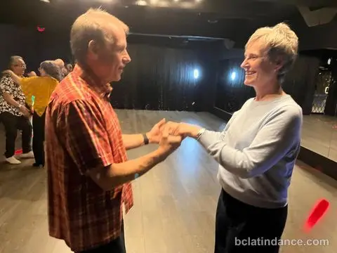 Two dancers smiling through the hand connection at Friday Salsa Night, Spencer Studios, Chilliwack