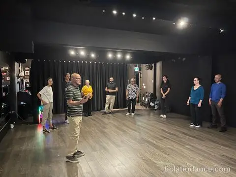 The class standing in a wide circle around the studio as Salsa Paul walks through the first move at Friday Salsa Night, Spencer Studios, Chilliwack